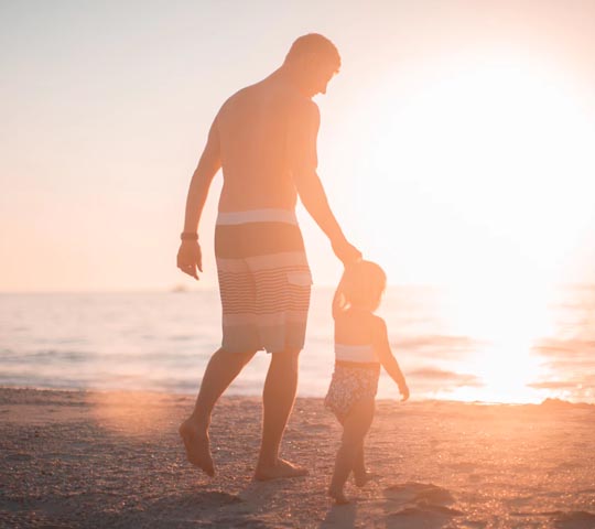 father and daughter on beach at sunset